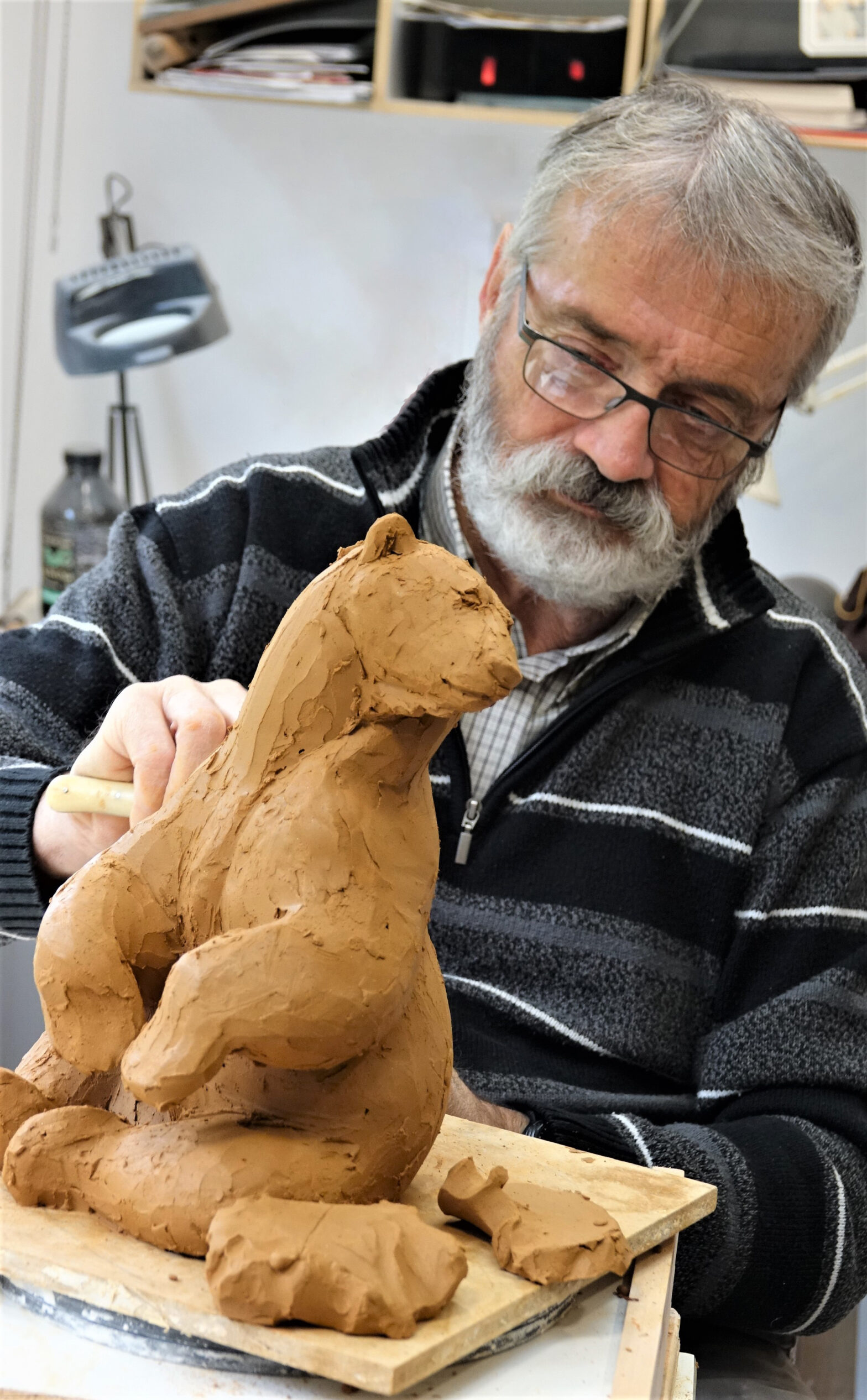 Photographie de Michel Bassompierre sculptant un ours en terre cuite.