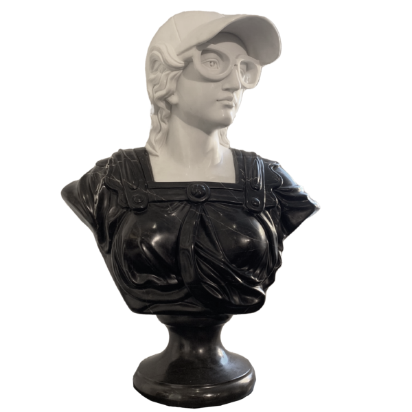 Cette image est une sculpture de l'artiste Léo Caillard, intitulée "Athena". Cette pièce unique de 75 cm, réalisée en marbre blanc et en marbre noir représente un buste de la déesse Athena, avec des attributs contemporains : une casquette et des grosses lunettes. Vous pouvez retrouver cette pièce à la Galerie Montmartre à Paris, France.