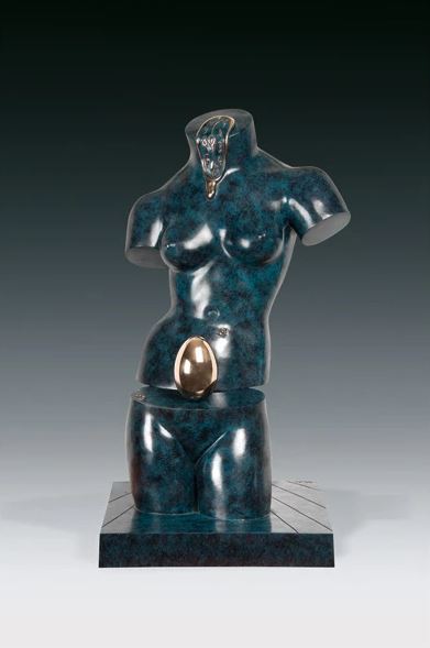Cette image représente une sculpture de l'artiste Salvador Dalí. Elle est réalisée en bronze à la cire perdue, aux couleurs bleues et dorées. En deux parties, elle représente un buste nu et des hanches de femme qui sont fendues horizontalement en deux, avec un oeuf doré et une horloge fondue. Elle mesure 63,5 cm et est exposée à la Galerie Montmartre à Paris, France.
